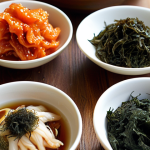 **Close-up of various Korean superfoods (kimchi, seaweed, ginseng, green tea) arranged artfully on a wooden table, bathed in natural light. Focus on vibrant colors and textures.**